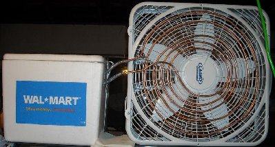 The entire unit, sitting on a parts rack.  I need to move it lower so ice swaps don't require a step stool.<br />The connection between the copper and vinyl tubes leaks a bit.  You can see the paper towel that catches the slow dripping.<br />You can see the condensation stop mid way through the copper coil.  The heat transfer is pretty good.
