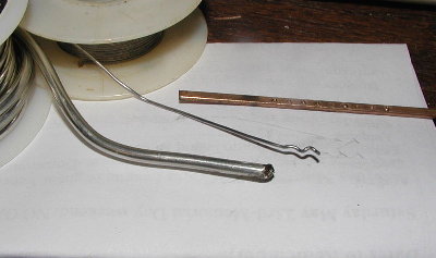 Silver bearing solder is in front.  Nice and shiny  with a silver color.  Behind it is electrical lead tin electrical solder.  The copper colored rod is 15% silver brazing solder.  On copper pipe it looks a lot like electrical solder in color, but it is very hard.  Soft lead based solder will write on paper.  The other two will not rub off on paper.