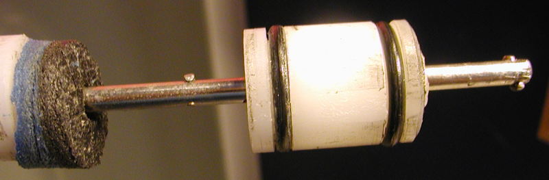 I just shot a picture to show the detail of the two pins that move the piston.  At the far left is the end of the stopper assy behind the bumper.  That poor bumper looks like it is due replacement.  It has taken a beating.<br /><br />The pin doesn't need to be huge and strong. The piston is easy to move.