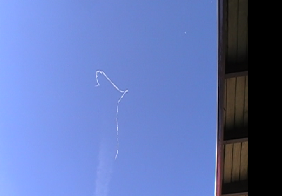 We had a small breeze.  The tape drifted over a 2 story building and the next building before landing next to the property line.  The building is an old school.  The roof in the photo is the roof of the gym.