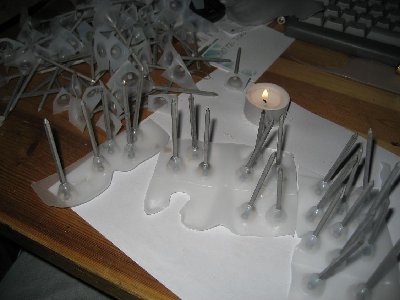 Milkjug heated until clear, then pressed onto the laserpointers head, which is resting on the table. when hardened, nail is pushed into the cone.